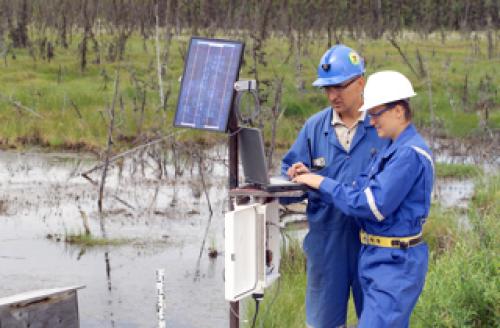 An image of two employees checking data at a monitoring station